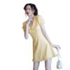 Model wearing yellow bellflower a-line dress with puff sleeves ruffle hem front buttons holding white purse